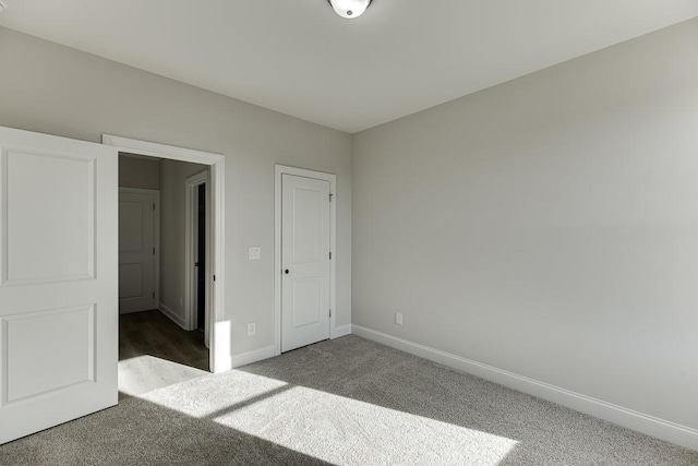 unfurnished bedroom with dark colored carpet and a closet