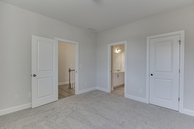 unfurnished bedroom featuring light colored carpet and ensuite bathroom