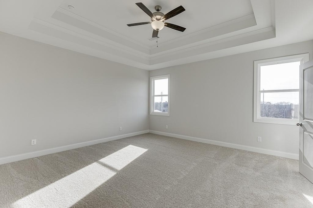 carpeted empty room with a raised ceiling, ceiling fan, and crown molding