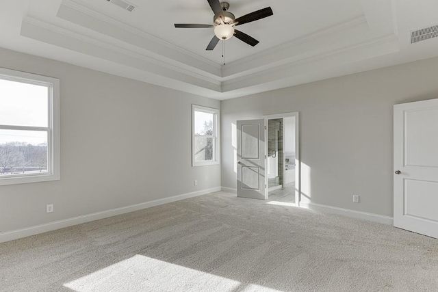 carpeted empty room with ceiling fan, crown molding, and a raised ceiling