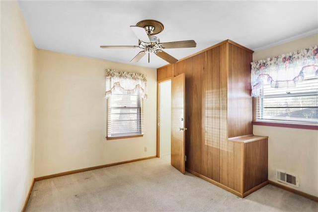 unfurnished bedroom featuring light carpet, a ceiling fan, visible vents, and baseboards