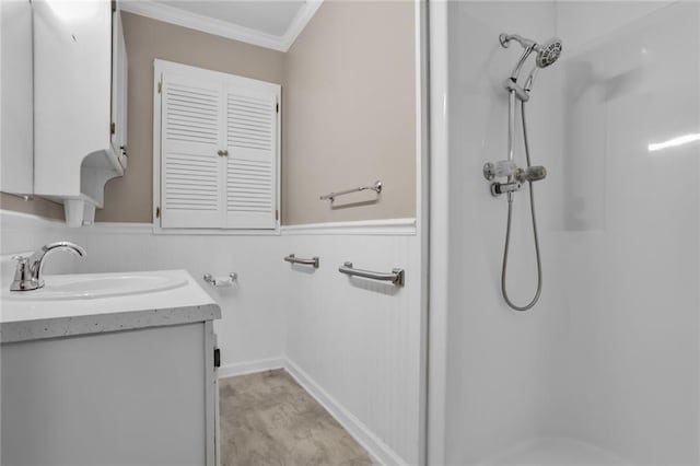 full bathroom with a wainscoted wall, ornamental molding, walk in shower, and vanity