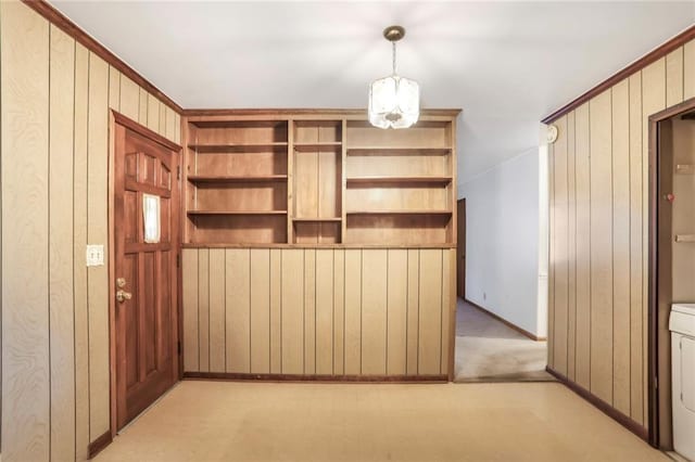 interior space featuring light carpet, washer / dryer, and wooden walls