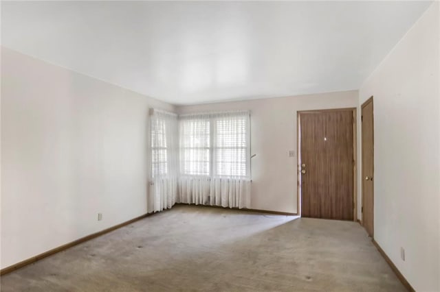 empty room featuring baseboards and light colored carpet