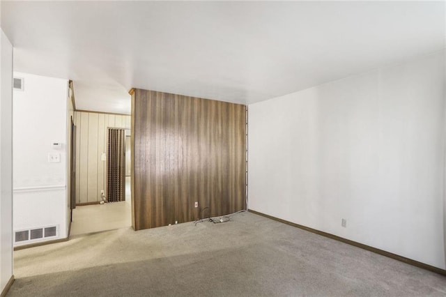 empty room with baseboards, visible vents, and light colored carpet