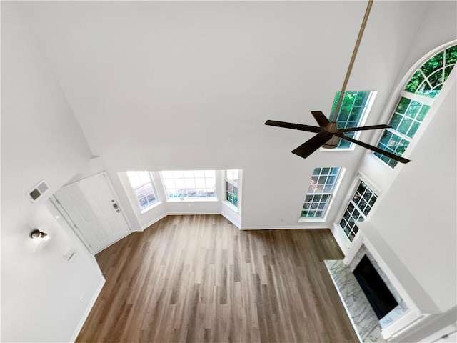 interior space with a towering ceiling, hardwood / wood-style flooring, and ceiling fan