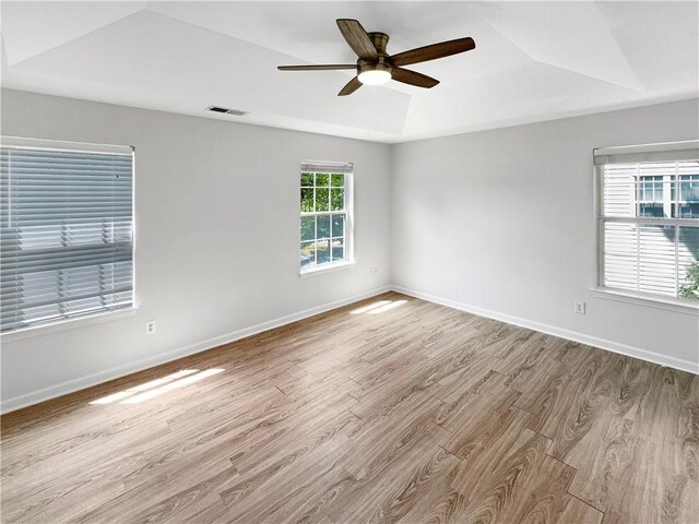 spare room with a raised ceiling, light hardwood / wood-style flooring, and ceiling fan