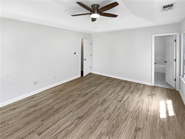 unfurnished room featuring a tray ceiling, ceiling fan, and tile patterned flooring