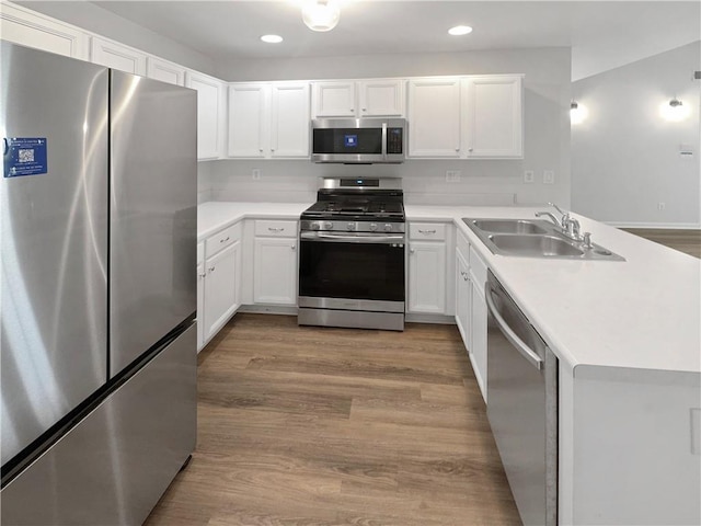 kitchen featuring light wood-type flooring, sink, appliances with stainless steel finishes, and white cabinetry