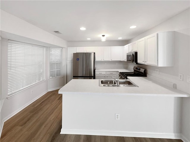 kitchen with appliances with stainless steel finishes, dark hardwood / wood-style flooring, and kitchen peninsula