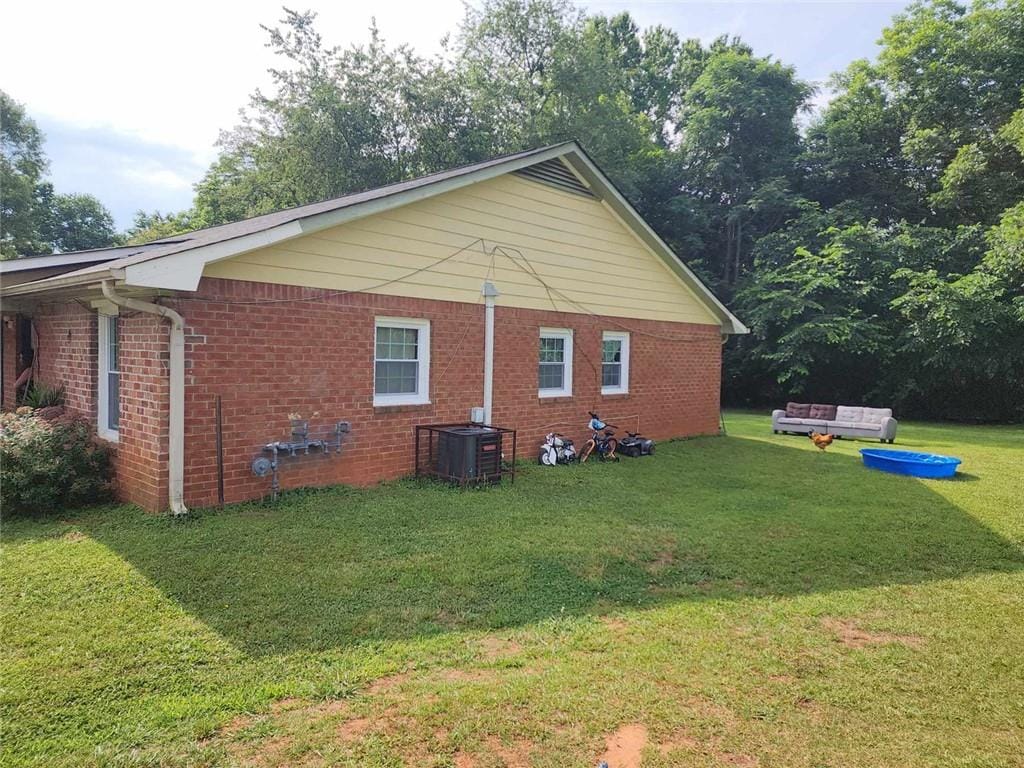 view of side of home with central AC unit and a yard