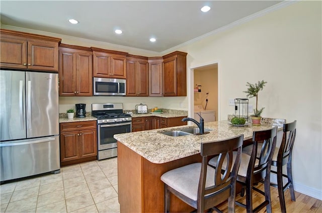 kitchen with a breakfast bar, light tile patterned flooring, sink, crown molding, and stainless steel appliances