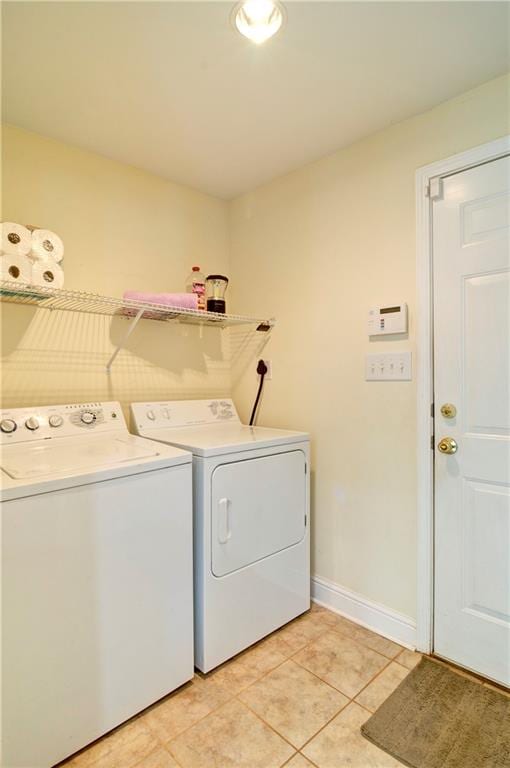 clothes washing area featuring light tile patterned floors and washer and dryer