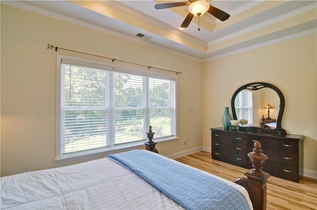 bedroom featuring ceiling fan, multiple windows, and a tray ceiling