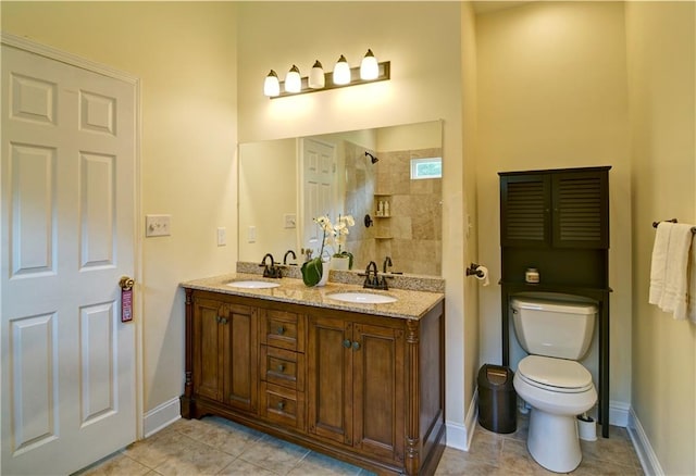 bathroom featuring tile patterned flooring, toilet, a tile shower, and vanity