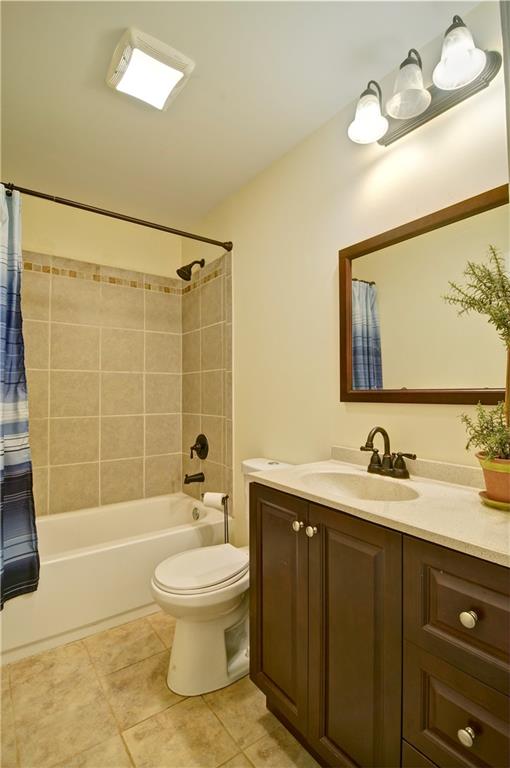 full bathroom featuring shower / tub combo with curtain, toilet, vanity, and tile patterned floors