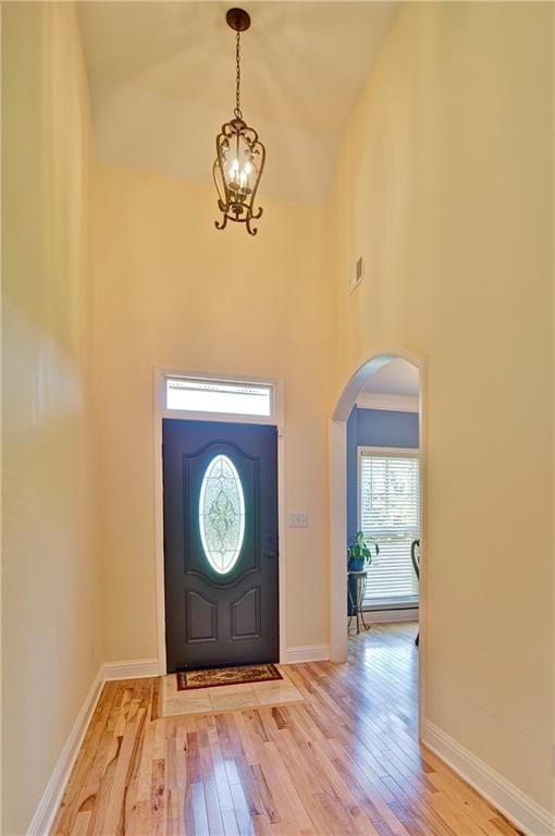 entryway with a high ceiling, light hardwood / wood-style floors, and an inviting chandelier