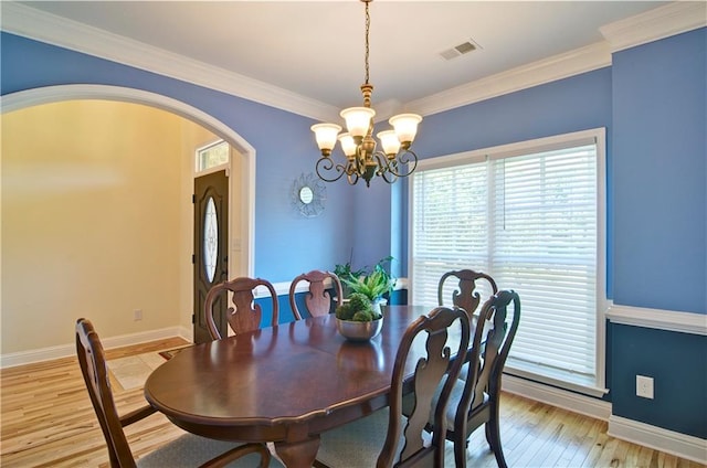 dining space with light hardwood / wood-style floors, a notable chandelier, and ornamental molding