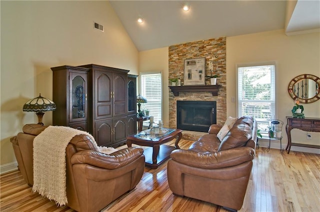 living room featuring a fireplace, high vaulted ceiling, and light wood-type flooring