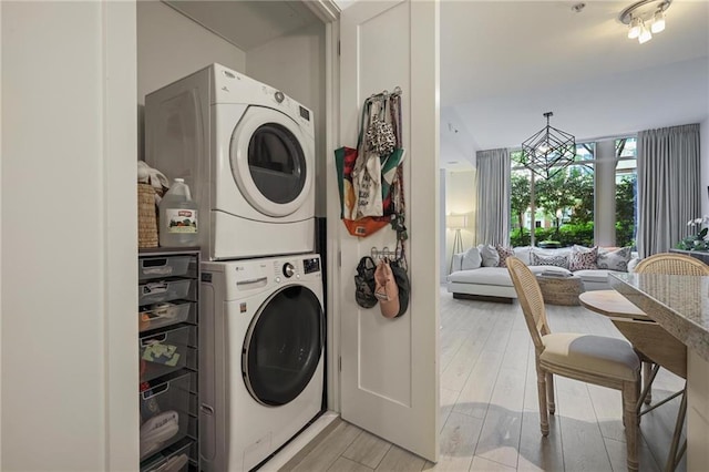 laundry room with estacked washer and dryer and light wood-style floors
