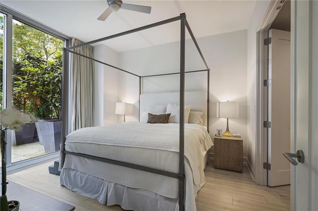 bedroom featuring light wood-style floors, ceiling fan, and a wall of windows