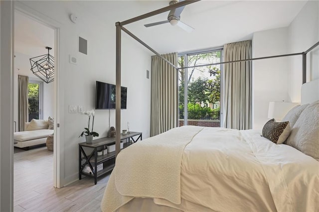 bedroom featuring multiple windows, light wood-style flooring, a ceiling fan, and baseboards