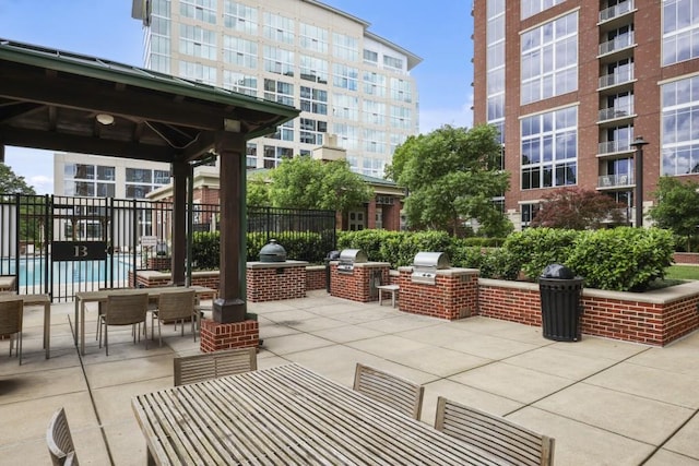 view of patio with exterior kitchen, fence, a grill, a gazebo, and outdoor dining space