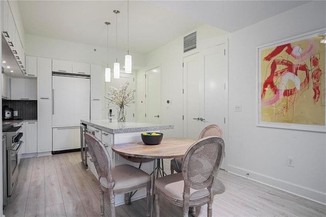 dining space featuring light wood-style flooring and baseboards