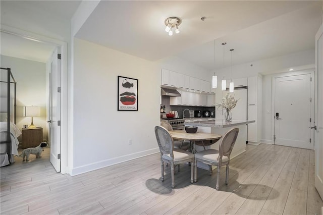 dining space with light wood-style flooring and baseboards