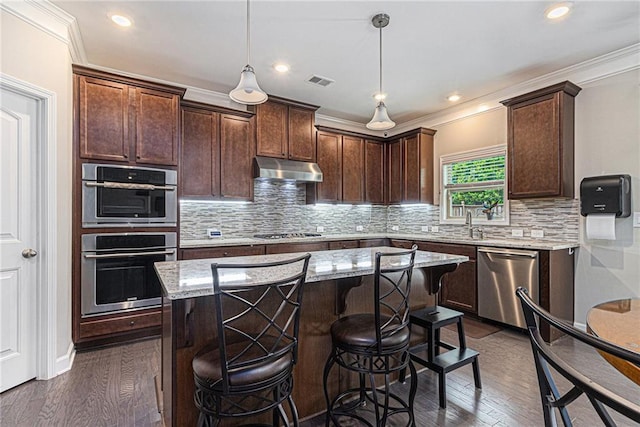 4815 Edgemoore Trce, Cumming, GA 30040 - kitchen featuring appliances with stainless steel finishes, under cabinet range hood, light stone counters, a center island, and a kitchen breakfast bar