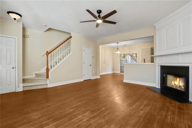 unfurnished living room featuring ceiling fan with notable chandelier and dark hardwood / wood-style floors