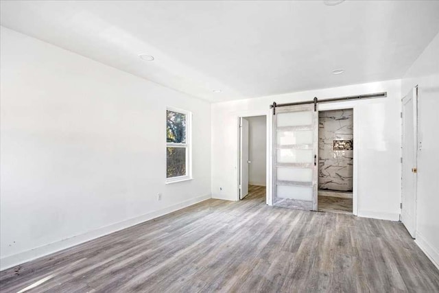 unfurnished bedroom featuring light hardwood / wood-style floors and a barn door