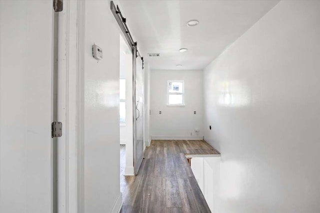 corridor featuring dark hardwood / wood-style flooring and a barn door