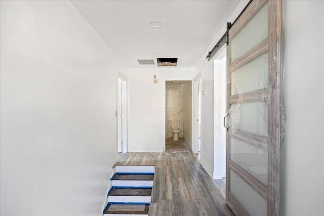 corridor featuring a barn door and hardwood / wood-style flooring