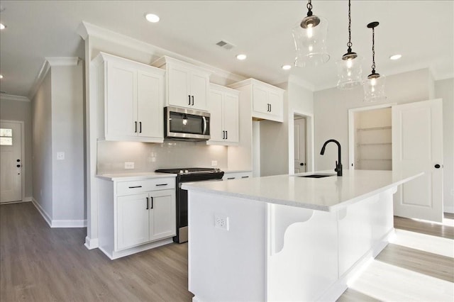 kitchen with appliances with stainless steel finishes, a kitchen island with sink, sink, pendant lighting, and white cabinets