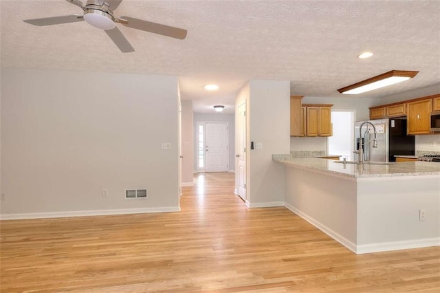662 Shady Willow Ln, Loganville, GA 30052 - kitchen with a textured ceiling, light wood finished floors, stainless steel appliances, a sink, and brown cabinetry