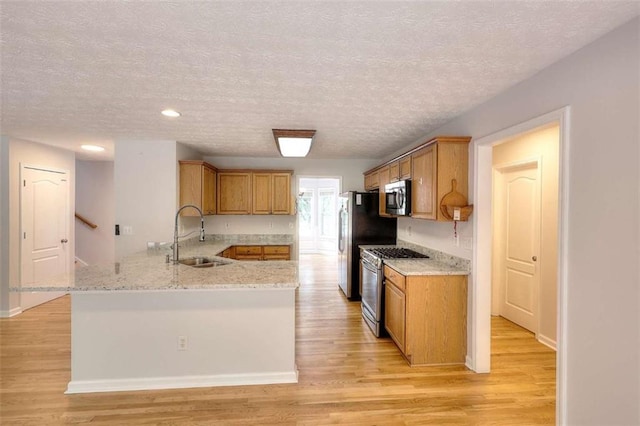 662 Shady Willow Ln, Loganville, GA 30052 - kitchen with stainless steel appliances, a sink, a textured ceiling, a peninsula, and light stone counters