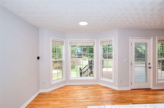 662 Shady Willow Ln, Loganville, GA 30052 - unfurnished dining area featuring baseboards, a textured ceiling, light wood-style flooring, and plenty of natural light
