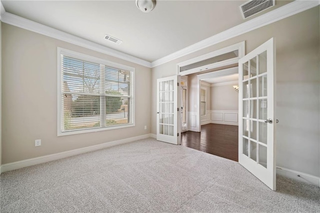 unfurnished room with visible vents, french doors, crown molding, and carpet floors