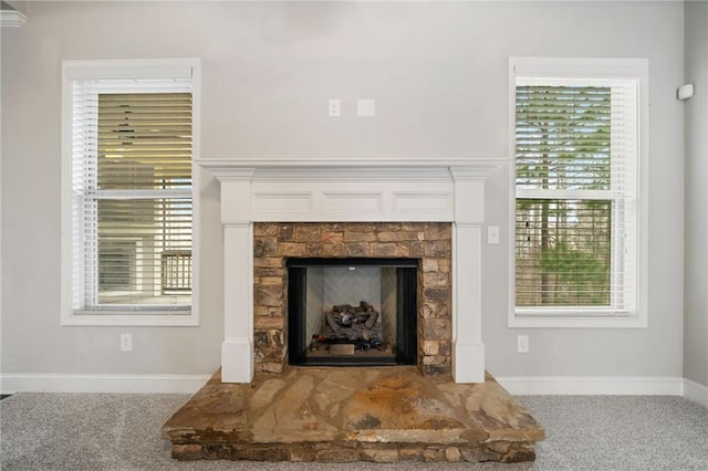 details featuring carpet flooring, a fireplace with raised hearth, and baseboards