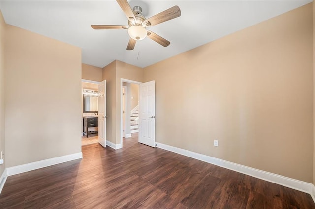 spare room featuring dark wood-style floors, a ceiling fan, and baseboards