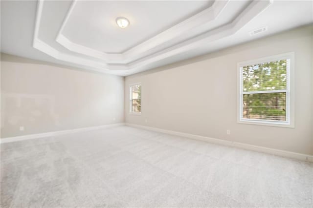 unfurnished room with light colored carpet, baseboards, and a tray ceiling