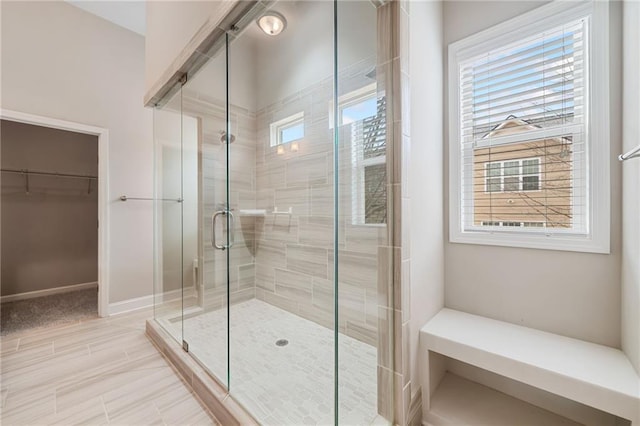 full bathroom with a spacious closet and a stall shower