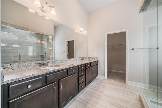 bathroom featuring a shower stall, a spacious closet, double vanity, and a sink