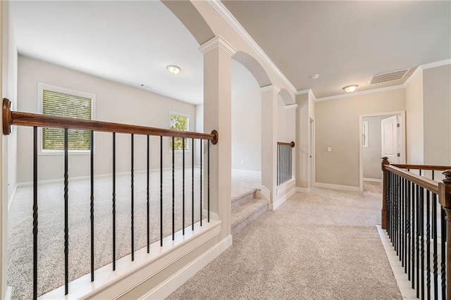 hall with visible vents, arched walkways, carpet floors, crown molding, and baseboards