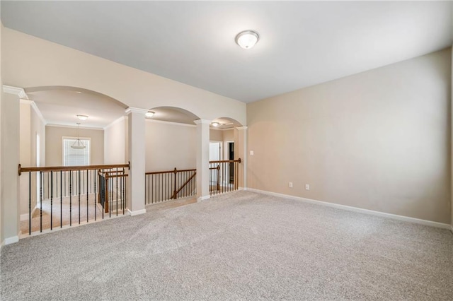 empty room featuring carpet, arched walkways, baseboards, and ornate columns