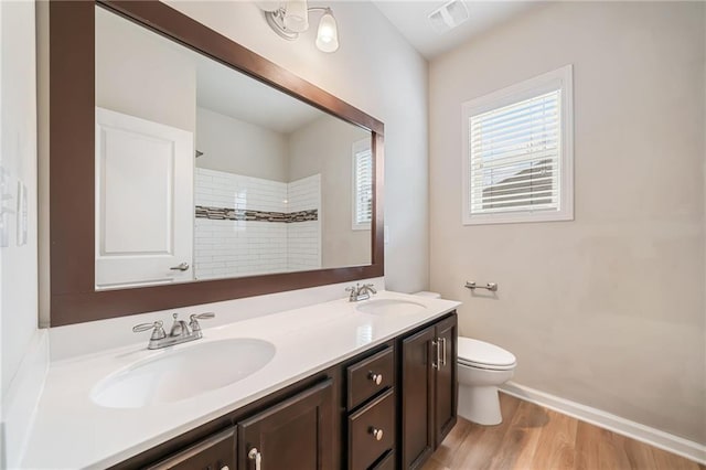 bathroom with double vanity, toilet, visible vents, and a sink