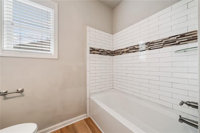 bathroom with toilet, shower / bathtub combination, baseboards, and wood finished floors