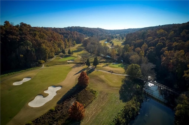 drone / aerial view with view of golf course, a water view, and a forest view
