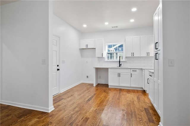 kitchen featuring backsplash, white cabinetry, sink, and light hardwood / wood-style floors